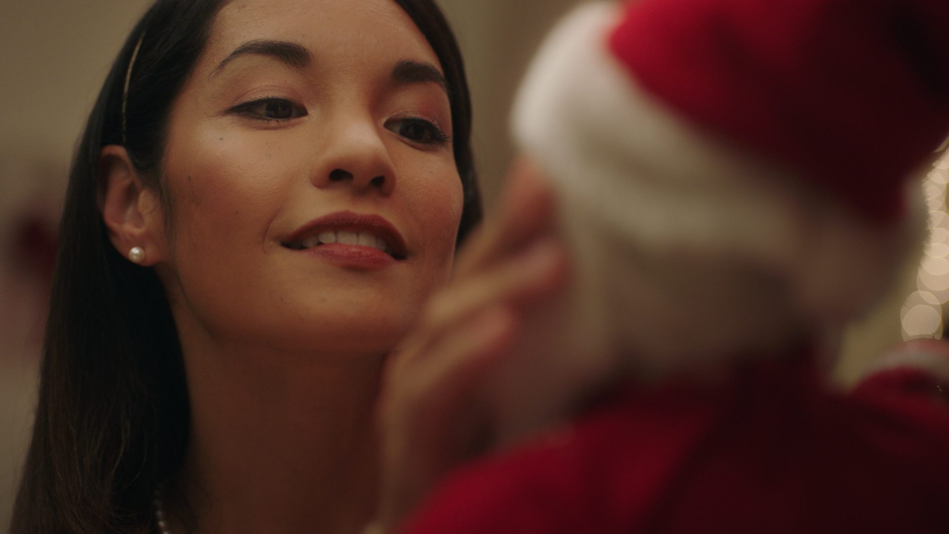 A woman smiling, a red hat just out of focus beside her