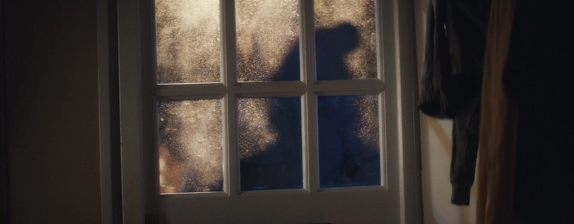The figure crosses the doorway